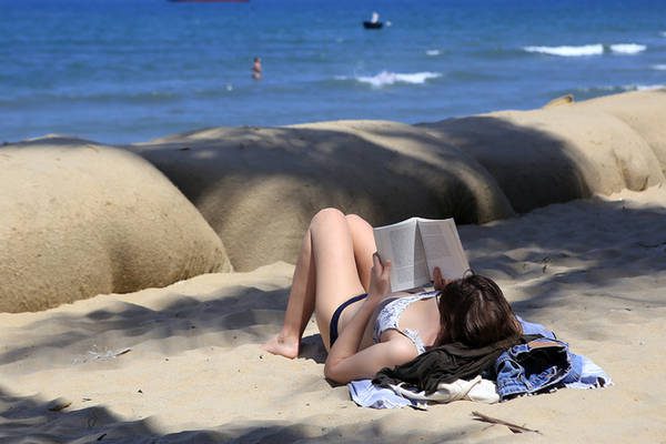 Một du khách thư thái nằm trên bãi cát ở Cửa Đại đọc sách. Một chủ nhà hàng ven biển cho biết du khách trở lại ngày một đông, giúp việc buôn bán dần nhộn nhịp sau hơn 3 năm.