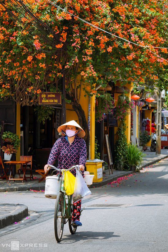 Người bán hàng đeo khẩu trang, đạp xe tại khu vực đường Trần Phú, giao với đường Hoàng Văn Thụ. Hội An có những con đường ngắn và hẹp, chạy dọc ngang theo hình bàn cờ, cứ đi hết hẻm này lại gặp hẻm khác.